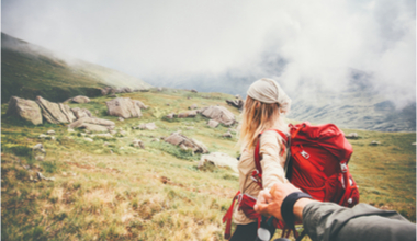 Couple helping each other up a mountain